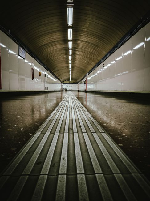 At Ponders End station, the platform is visible with a clean tiled surface and well-maintained wooden benches. The station canopy features white scalloped edging underneath a dark supporting structure